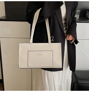 Close-up of off-white leather tote bag featuring elegant stitching and front pocket detail