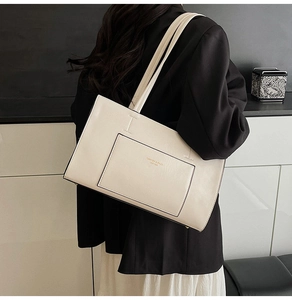 Close-up of beige leather tote bag featuring a front pocket with gold fashion lettering