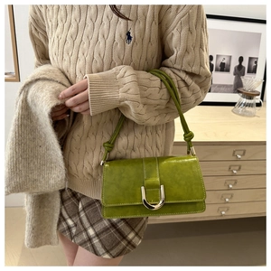 Détail d'un sac sous le bras en cuir vert avec boucle en U dorée et lanière à nœud élégante