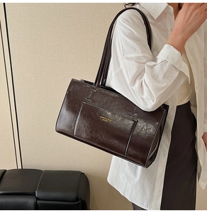 Detailed view of brown leather tote bag featuring contrast stitching and gold lettering