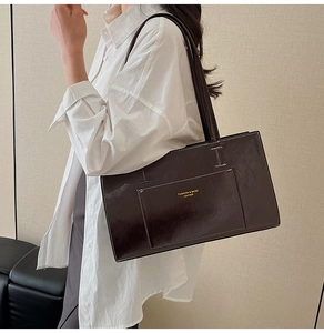 Detail of glossy leather tote bag with thin shoulder straps and gold fashion branding