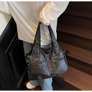 Sac fourre-tout noir vintage en similicuir avec détails de fermeture éclair sur un escalier
