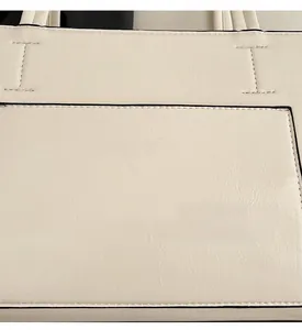 Detail of ivory leather shoulder bag showing fine texture and golden stamped text