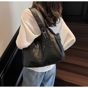 Détail du grand sac cabas noir avec texture en cuir souple et boucles métalliques