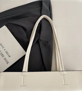 Detail of cream leather tote bag featuring durable double handles and fine stitching quality