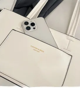 Detail of the front pocket on the cream leather tote bag showing storage for a phone