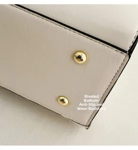 Detail view of cream leather handbag base with gold protective metal rivets