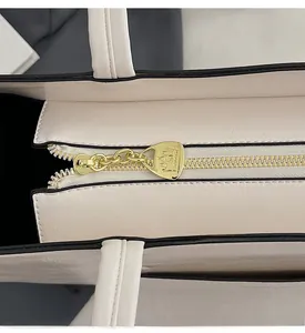 Close-up of beige leather shoulder bag featuring a premium gold crown embossed zipper slider
