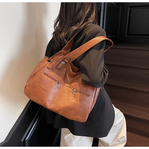 Detail of vintage brown oil wax leather tote bag featuring functional dual metal zippers