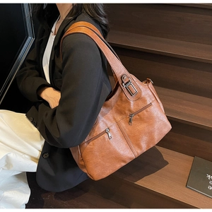 Détail d'un grand sac cabas vintage marron avec zips fonctionnels sur un escalier en bois
