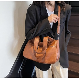 Détail d'un sac cabas en cuir marron avec poches zippées et bandoulière réglable
