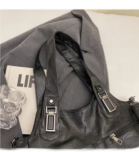 Detail van zwarte draagtas met litchi-leertextuur en zilveren metalen hardware