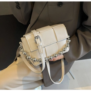 Close-up of beige woven leather crossbody bag with silver bead chain and metal strap detail