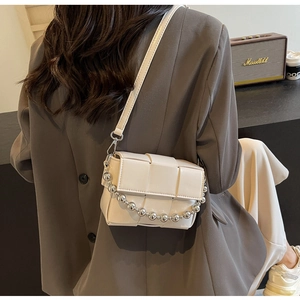 Detail of off-white woven crossbody bag with metallic bead chain and leather strap