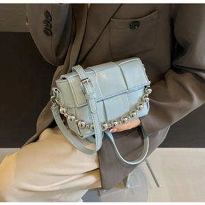 Detail of light blue woven crossbody bag with stylish silver bead chain handle and texture