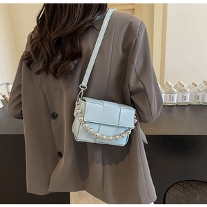 Detailed view of light blue woven crossbody bag with silver decorative chain beads