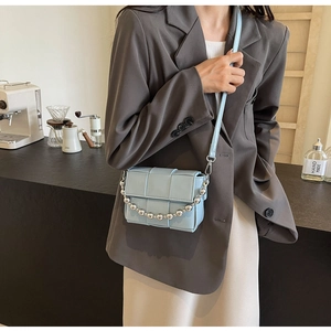 Lifestyle view of light blue woven crossbody bag with silver ball chain on a model