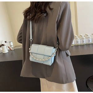 Close-up of light blue woven leather crossbody bag with silver decorative chain detail