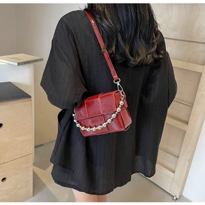 Detail view of woven leather bag in burgundy with silver chain strap and long shoulder strap