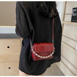 Detail of dark red woven pattern bag with a decorative silver bead chain strap