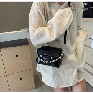 Close-up of black woven crossbody bag with silver bead chain and leather strap