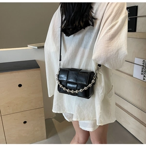 Detailed view of the woven texture and silver bead chain on the black leather crossbody bag
