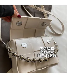 Detail view of woven leather bag featuring silver magnetic clasps and bead handle
