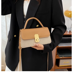 Détail du sac à main bicolore en cuir et tissu avec fermoir rotatif doré élégant