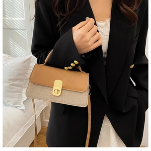 Detail of beige textured handbag with tan leather flap and golden twist lock closure