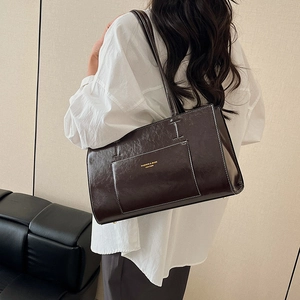 Dark brown leather tote bag with white contrast stitching and a front pocket