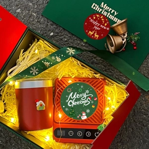 Coffret cadeau de Noël avec tasse rouge et chauffe-tasse électrique sur papier festif