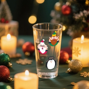 Verre de Noël avec motifs Père Noël et lutin parmi des décorations de fête