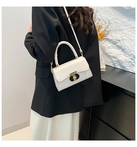 White polished leather mini bag with gold ring clasp worn with a black blazer