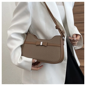 Détail du sac sous le bras en tissu marron avec bordure en cuir et boucle papillon