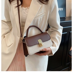 Close-up of woven cream texture and brown leather flap with gold twist-lock on handbag