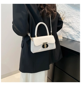 Detail view of a creamy white glossy leather bag with metal twist lock and slim strap