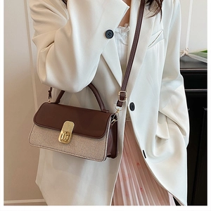 Détail d'un sac à main tissé bicolore avec boucle dorée vintage porté par un mannequin
