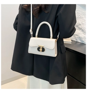 Detail of cream-white leather handbag with signature gold buckle on a black blazer