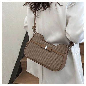 Détail d'un sac sous le bras marron tressé avec nœud en cuir porté par un mannequin