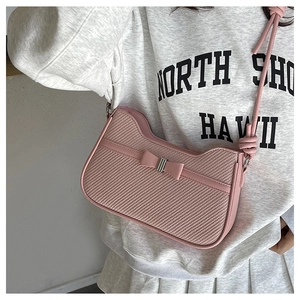 Gros plan du sac bandoulière rose en similicuir et tissu tressé avec nœud décoratif