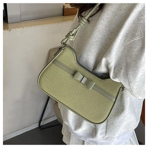 Détail du sac tissé vert sauge avec un nœud en cuir et une bandoulière à design noué