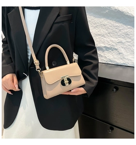 Close-up of beige leather square bag with golden buckle styled with black blazer