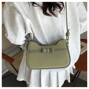 Détail du sac baguette en tissu vert clair avec nœud et poignée en forme de chat