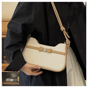 Détail d'un sac bandoulière blanc tissé avec garniture en cuir marron et nœud
