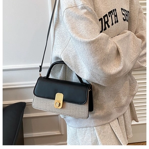 Detail showing contrast stitching texture and gold clasp on the crossbody bag