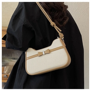 Détail du sac sous l'aisselle en tissage blanc avec bordure en cuir beige et nœud décoratif
