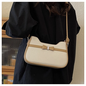 Gros plan d'un sac bandoulière en tissu tissé avec garniture en cuir brun et nœud