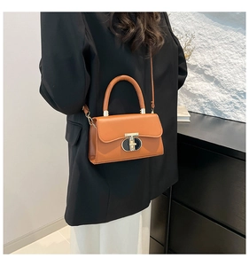 Detailed view of the orange crossbody bag with stylish gold and black T-shaped metal lock