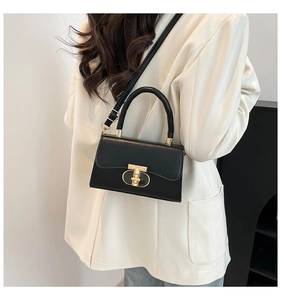 Close-up of elegant black leather handbag with unique gold double-ring clasp closure