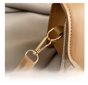 Detail eines hochwertigen Goldhakens an einer beigen Leder- und Stoffhandtasche
